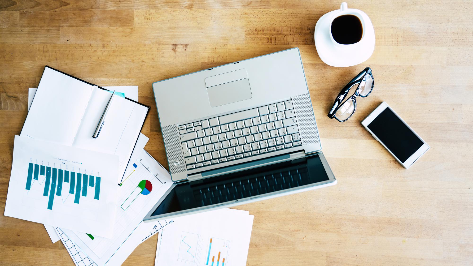 Office desk with financial reports and laptop